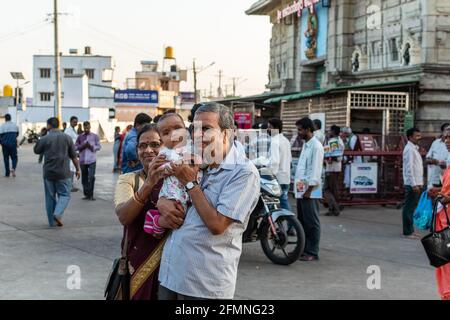 Mysore, Karnataka, Indien - Januar 2019: Zwei indische Großeltern halten ein Kind und posieren für ein Bild vor dem alten Chamundeshwari-Tempel in Stockfoto
