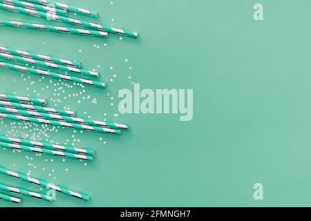 Metallische und türkisfarbene Papierhalme und glänzendes Glitter-Konfetti Stockfoto