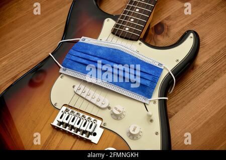 Schützende chirurgische Gesichtsmaske, die ein Elektrikgitarren-Symbol für Schweigen umhüllt Kreative während der Corona-Virus-Krankheit Pandemieausbruch vertikales Bild wo Stockfoto