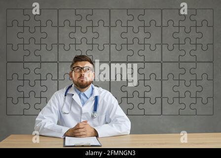 Arzt im Laborkittel, der am Schreibtisch sitzt und anschaut Hintergrund mit kompletten Puzzle Stockfoto