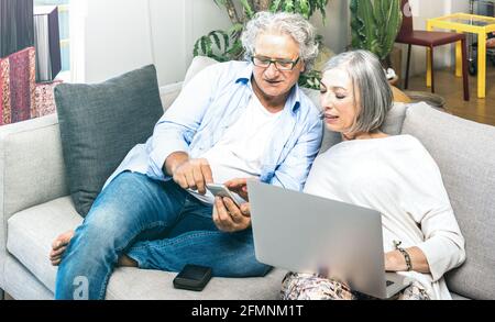 Rentnerpaar mit Laptop-Computer zu Hause auf dem Sofa - Ältere und Technologiekonzept mit reifen Menschen im Internet Einkaufen - moderne Lage Stockfoto