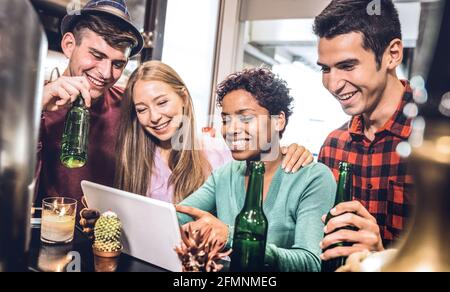 Multirassische Freunde trinken Bier und haben Spaß mit Tablet an Cocktailrestaurant – Freundschaftskonzept, in dem junge Menschen Spaß haben Gemeinsam Stockfoto