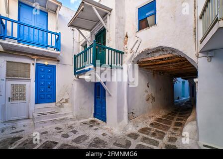 Traditioneller Innenhof oder Sackgasse in engen Gassen griechischer Städte auf den Kykladen. Authentische weiß getünchte Wände, blaue Türen und Fensterläden, Pflastersteinpflaster Stockfoto