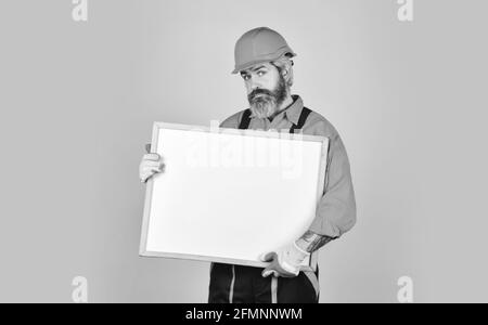 Mann in harter Mütze. Builder zeigt auf Flipchart. Architekt Arbeiter halten Flipchart. Präsentieren Flipchart bei der Sitzung. Männliche Bauarbeiter. Copy Raum Stockfoto