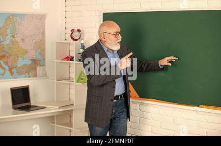 Oberlehrer erklären Thema an der Tafel. Lehrer für Geographie. Klassenzimmer mit Karte. Zurück zur Schule. Bildung in der modernen Schule. Bärtiger Mann zeigen Stockfoto
