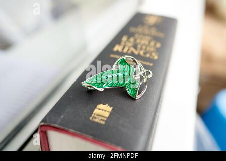 Grüne Brosche auf Herr der Ringe Buch. Die Blätter von Lorien waren Broschen von Galadriel an die Mitglieder der Fellowship of the Ring am Ende Stockfoto