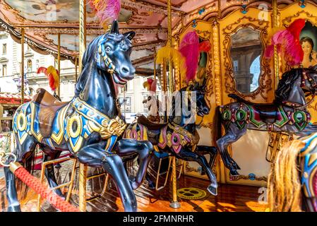 FLORENCE, ITALY - Aug 24, 2020: Florence, Toscana/Italy - 24.08.2020: Ein sehr hübsches und aufwendig dekoriertes Kinderkarussell mit schwarzen Pferden und einem großen Kinderkarussell Stockfoto