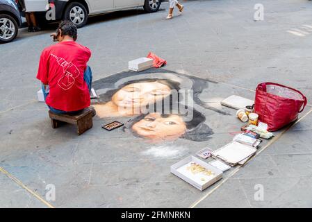 FLORENCE, ITALY - Aug 24, 2020: Florence, Toscana/Italy - 24.08.2020: Ein Straßenmaler malt ein Bild auf dem Bürgersteig, das eine Frau und ein Kind zeigt Stockfoto