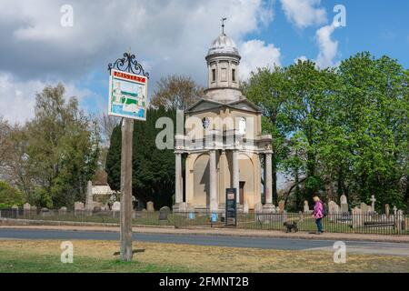 Mistley Essex, Blick auf das Dorfschild von Mistley auf dem Grün mit einem der beiden von Robert Adam entworfenen Türme aus dem Jahr 1776 Visible, Essex, Großbritannien Stockfoto