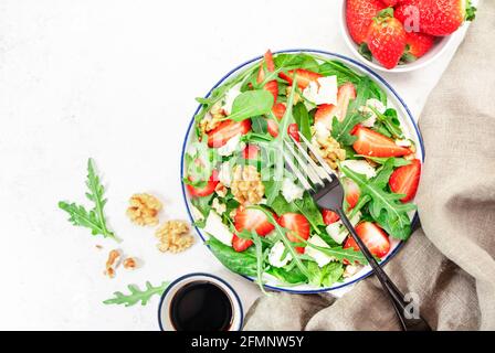 Erdbeersalat mit Spinat, Rucola, Walnüssen, Blauschimmelkäse auf grauem Tisch. Gesunde Ernährung. Draufsicht Stockfoto