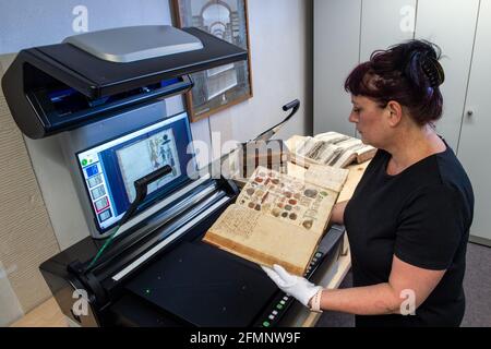 11. Mai 2021, Sachsen-Anhalt, Halle (Saale): Carmela Kahllow, Archivarin der Francke-Stiftungen in Halle/Saale, digitalisiert historische Bände aus dem Stiftungsbestand mit einem leistungsstarken Scanner. Die Stiftungen wollen die Digitalisierung ihres kulturwissenschaftlichen Bestandes erhöhen. Zu diesem Zweck wurde die Institution im Rahmen der staatlichen Digitalisierungsoffensive mit Mitteln für den Kauf eines hochmodernen Scanners ausgestattet. Nun soll die systematische Digitalisierung im Studienzentrum vorangetrieben werden. Die Francke-Stiftungen gehen auf den evangelischen Pfarrer August Herrmann Francke zurück. Er Stockfoto