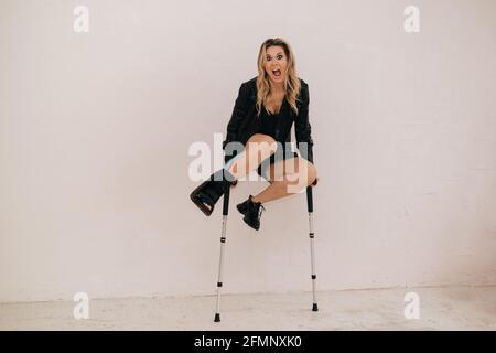 Krankenversicherung und Unfallkonzept. Humor Foto. Junge Frau springt auf Burgen. Bein in Gips und mit Kineso-Flecken. Stockfoto