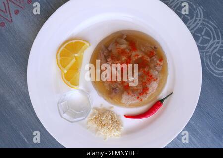 Ungarisches Schweinefleisch in Gelee, Kocsonya, mit roter Chili, Zitrone, geriebenem Meerrettich, Paprika, begleitet von einem Glas Palinka (ungarischer Obstbrand). Stockfoto