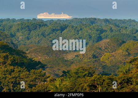 Grüner tropischer Dschungel-Wald mit großem Kreuzfahrt-Chip auf dem Meer. Exotische Landschaft im Carara NP in Costa Rica. Großes Boot im Wasser, Segelreise entlang der Stockfoto