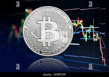 Bitcoin-Münze und Aktienchart Hintergrund mit sinkenden Preisen. Kryptowährung Stockfoto