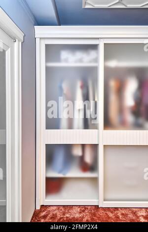 Großer, moderner Einbauschrank mit mattem Glas an den Schiebetüren Steht auf dem Boden mit Terrakotta-Teppich in Holzhaus bedeckt Stockfoto