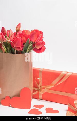 Schöne rote Tulpen in einer Geschenktüte und Geschenkschachteln. Vertikale Glückwünsche Foto alles gute zum Geburtstag, Valentinstag, Muttertag. Stockfoto