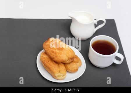 Hausgemachte zarte Profiterolen auf dem Tisch, eine Tasse Kaffee. Traditionelle französische Küche. Draufsicht. Stockfoto