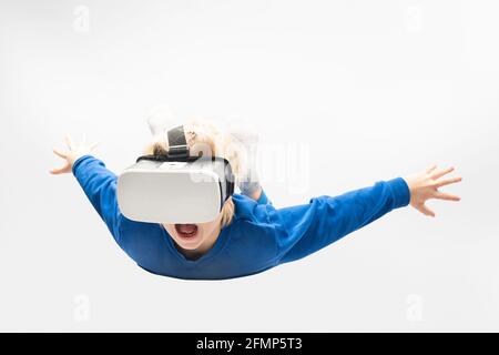 Kleiner Junge in Virtual-Reality-Brille fällt aus der Höhe. Weißer Hintergrund. Videospiele. Stockfoto