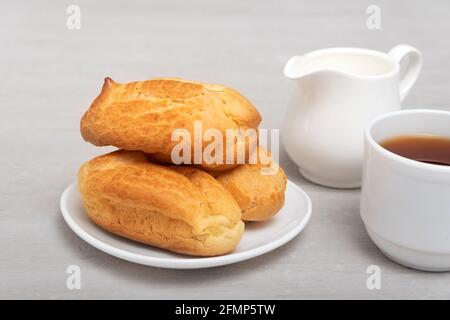 Hausgemachte Ecolirs und Tee mit Milch. Traditionelle französische Küche. Profiterolen auf weißer Untertasse Stockfoto