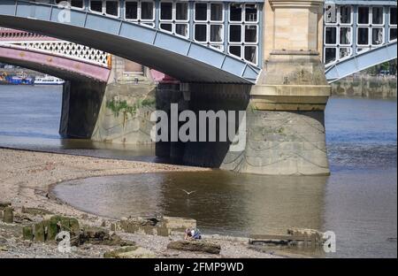 Bankside, London, Großbritannien. 11 Mai 2021. Ein Mann schlammt bei Ebbe am Südufer der Themse in der Nähe der Eisenbahnbrücke Blackfriars und jagt nach historischen Objekten, die vom zurücktretenden Wasser freigelegt wurden. Quelle: Malcolm Park/Alamy Live News. Stockfoto