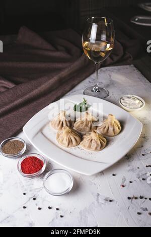 Georgische Hinkali auf einem weißen Teller mit Sauce im Restaurant. Stockfoto