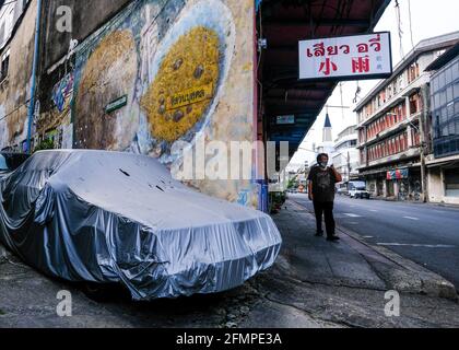 Ein Mann geht eine Straße entlang, in der Nähe eines riesigen Wandbildes, in der Chinatown-Gegend von Bangkok, Thailand Stockfoto