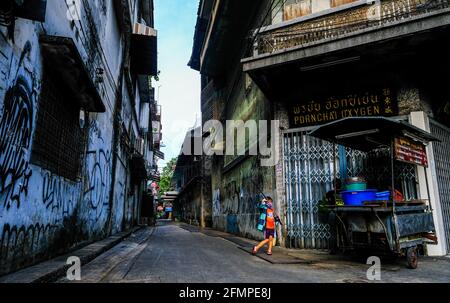 Ein kleiner Junge spielt am Eingang einer kleinen Gasse in Talat Noi, Bangkok, Thailand Stockfoto