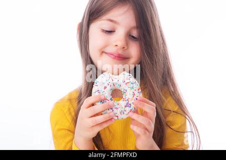 Süßes kleines Mädchen, das weißen Donut isst Stockfoto