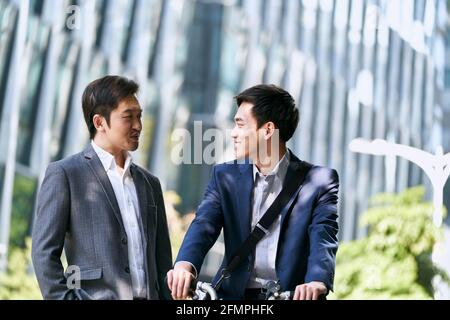 Zwei asiatische Geschäftspartner, die in der Innenstadt von ein Gespräch führen Moderne Stadt Stockfoto