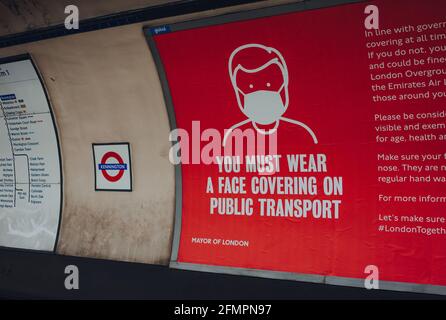 London, Großbritannien - 09. Mai 2021: Schild mit der Abdeckungsanforderung auf dem Bahnsteig der Londoner U-Bahn-Station Kennington. Die Anforderungen wurden eingeführt d Stockfoto