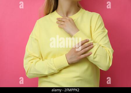 Junge Frau im gelben Sweatshirt vor rosa Hintergrund Stockfoto