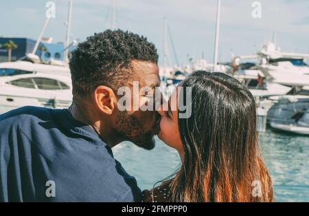 Nahaufnahme von interracial paar küssen im Hafen mit Boote Hintergrund im Sommer während der Ferien Stockfoto