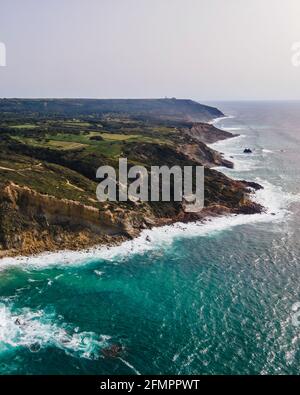 Luftaufnahme der wilden Küste mit Wellen des Atlantischen Ozeans, die auf den Klippen in der Nähe von Praia da Foz, Setubal, Portugal, Rollen. Stockfoto