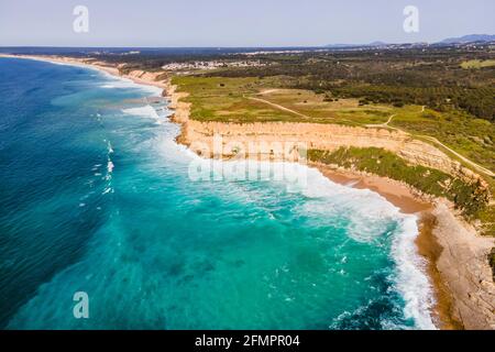 Luftaufnahme der wilden Küste mit Wellen des Atlantischen Ozeans, die auf den Klippen in der Nähe von Praia da Foz, Setubal, Portugal, Rollen. Stockfoto