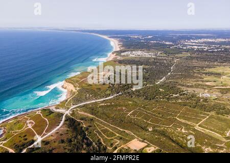 Luftaufnahme der wilden Küste mit Wellen des Atlantischen Ozeans, die auf den Klippen in der Nähe von Praia da Foz, Setubal, Portugal, Rollen. Stockfoto