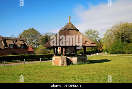 Ein Blick auf das reetgedeckte Brunnenhaus auf dem malerischen Dorfgrün in den Norfolk Broads in Woodbastwick, Norfolk, England, Großbritannien. Stockfoto