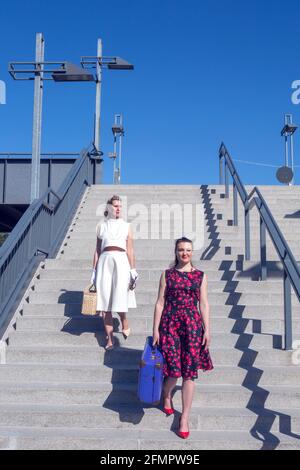 Zwei Frauen im Stil der 1950er Jahre, die im Freien mit Koffer unterwegs sind Treppen Stockfoto