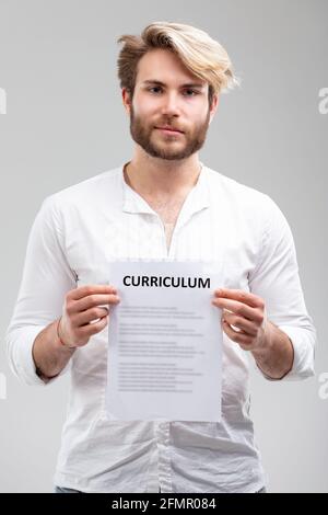 Studio schoss das Porträt eines hübschen jungen Mannes, der seine zeigt Qualifikation und Berufserfahrung im Curriculum oder lebenslauf bereit Für eine Änderung in seinem c Stockfoto