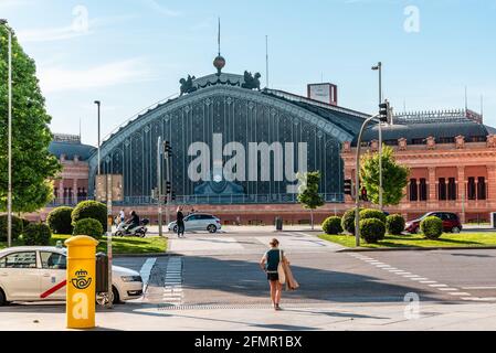 Madrid, Spanien - 1. Mai 2021: Außenansicht des alten Atocha Bahnhofs. Frau, die die Straße vor dem Bahnhof überquert Stockfoto