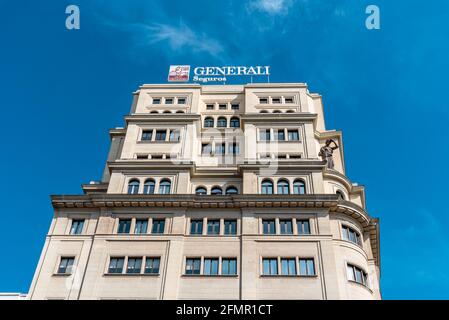 Madrid, Spanien - 8. Mai 2021: Altes Bürogebäude mit Generali Insurance Company Schild auf dem Dach. Blick aus dem niedrigen Winkel gegen den blauen Himmel Stockfoto