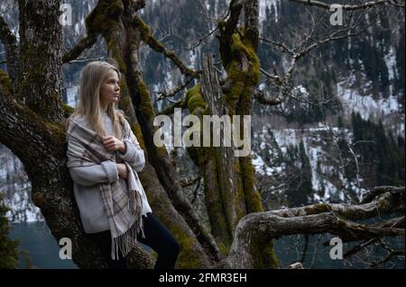 Das Mädchen sitzt auf einem Baum und meditiert in der Nähe des Ritsa-Sees In Abchasien Stockfoto