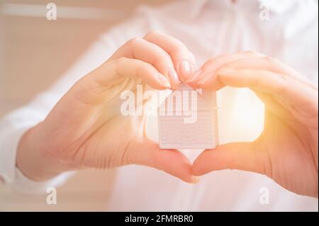 Hände halten Miniaturhaus. Wohnungs- und Hausschutz-Versicherungskonzept, Familienhaus, Hauskredit, Hausversicherung, Familienlebensversicherung Stockfoto