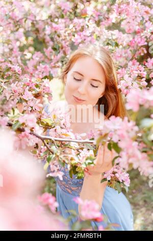 Mädchen inhaliert Duft von Kirschblüten im Garten, ohne zu sein Allergisch auf Pollen Stockfoto