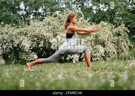 Ein junges, schlankes Mädchen dehnt sich im Park aus. Stockfoto