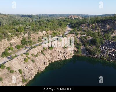 Felsige Ufer des Radon Lake an einem sonnigen Sommermorgen. Luftaufnahme eines alten überfluteten Granitsteinbruchs. Ein malerischer Teich. Stockfoto