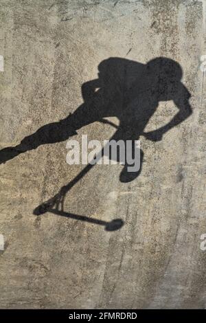 Der Schatten eines Stunt Scooter Riders, der Tricks auf EINER Betonhalbpfeife in EINEM Skate Park, Christchurch UK, macht Stockfoto