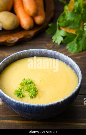 Frisch gekochte Kartoffelsuppe in einer Schüssel, garniert mit Petersilie Und Hauptzutaten im Rücken Stockfoto