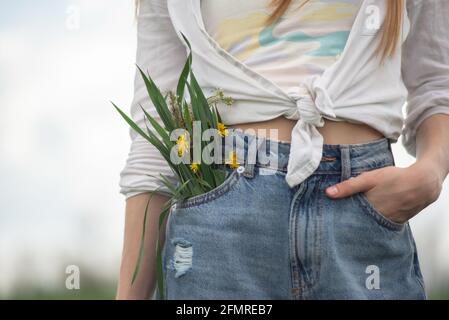 Nahaufnahme eines Blumenstraußes aus der Tasche der Denim-Hose eines Teenagers. Stockfoto