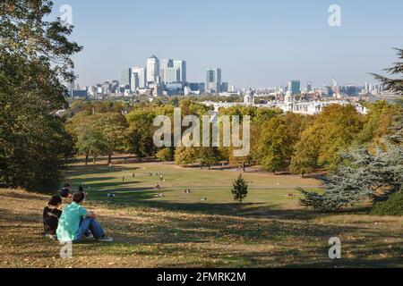 LONDON, Großbritannien - 03. Oktober 2011. Pärchen sitzen im Herbst im Greenwich Park und genießen den Blick auf Canary Wharf und die Skyline von London Stockfoto